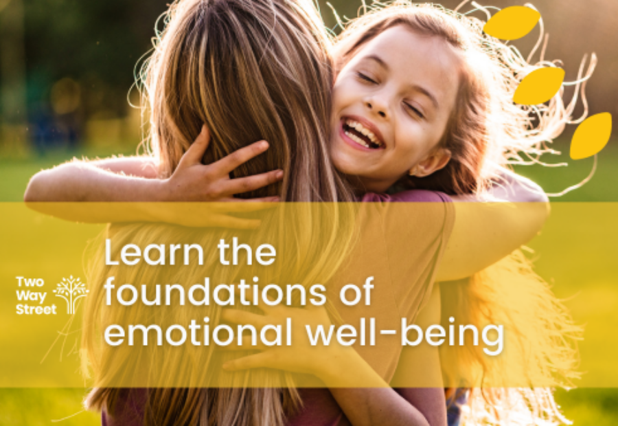 We see the back of a mother hugging a smiling child. Text reads 'Learn the foundations of emotional well-being'
