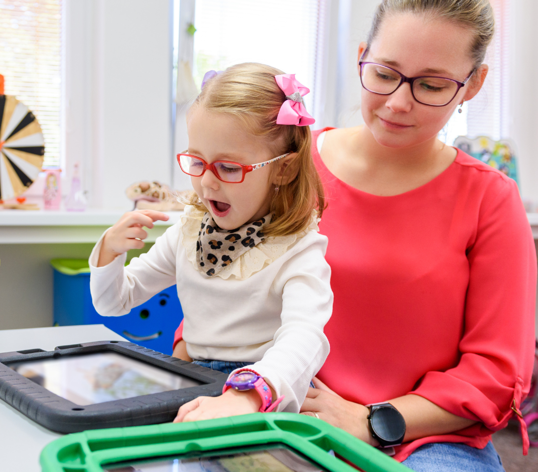 AAC parent with child looking at AAC devices