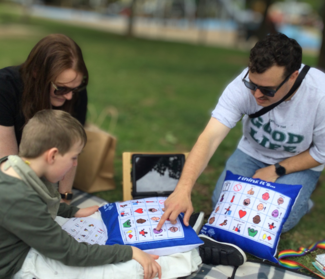 Speech therapist with clients in a park using AAC chat cushions to talk