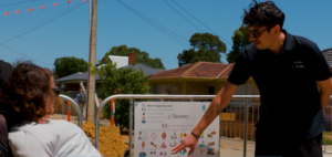 A worker is chatting with a customer while pointing to a communication board as they speak