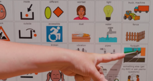 A person points to the symbol for 'footpath' on a communication board